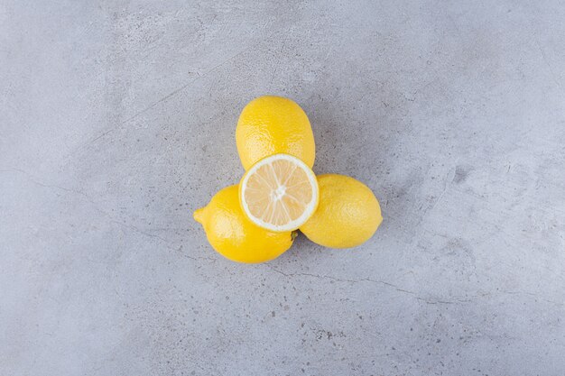 Frutas de limón enteras y en rodajas con hojas colocadas sobre la mesa de piedra.