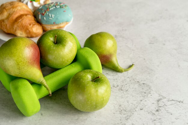 Frutas y mancuerna verde sobre hormigón texturado.