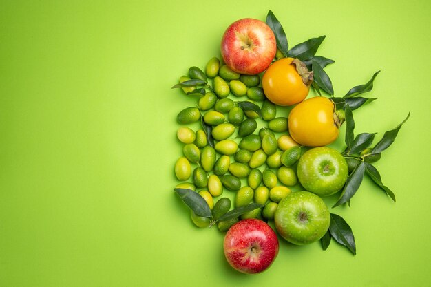 frutas manzanas caquis cítricos con hojas sobre la mesa