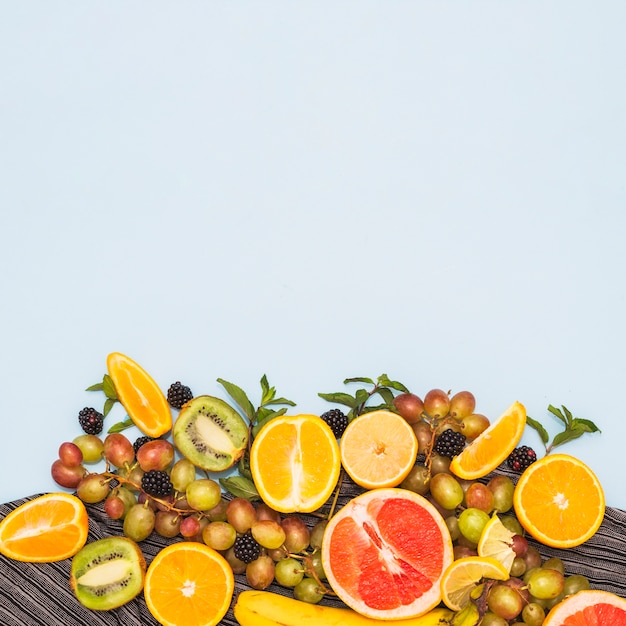 Frutas a la mitad; Uvas y moras sobre fondo azul.