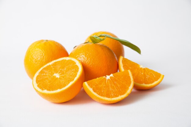 Frutas naranjas cortadas y enteras con hojas verdes