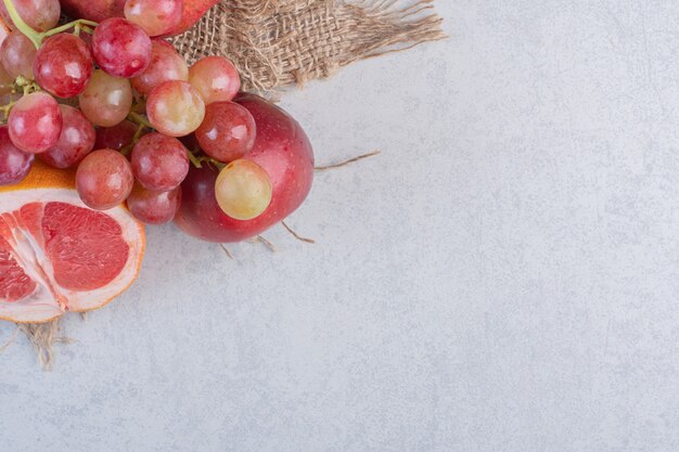 Frutas orgánicas frescas. Manzana, uvas y mandarinas sobre fondo gris.