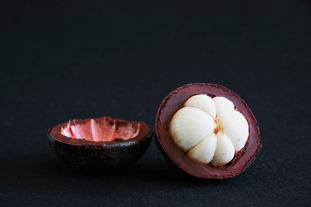 Frutas populares tailandesas del mangostán: una fruta tropical con segmentos de pulpa dulce y blanca dentro de una gruesa corteza de color marrón rojizo.