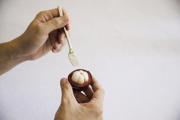 Frutas populares tailandesas del mangostán: una fruta tropical con segmentos de pulpa dulce y blanca dentro de una gruesa corteza de color marrón rojizo.