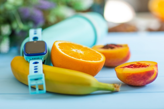 Frutas y reloj inteligente en el escritorio de madera azul