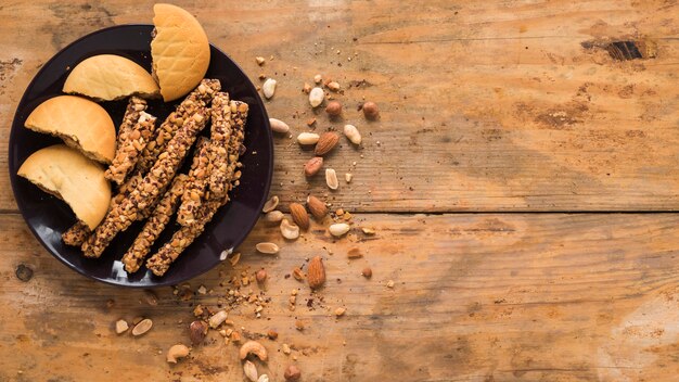 Frutas secas; Galletas y barra de granola sobre fondo con textura de madera