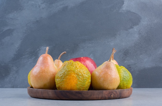 Foto gratuita frutas de temporada en placa de madera sobre fondo gris.