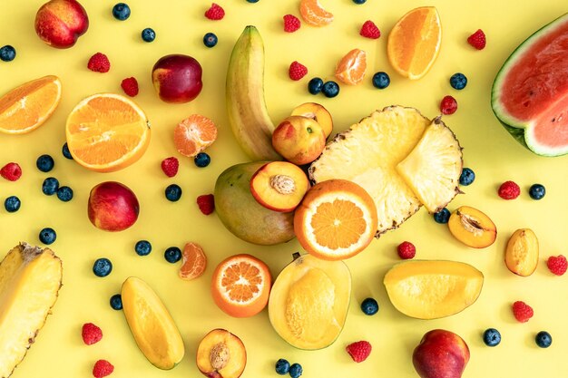 Frutas tropicales y bayas sobre un fondo amarillo plano