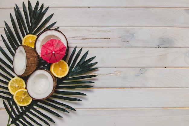 Frutas veraniegas y hojas de palma sobre superficie de madera