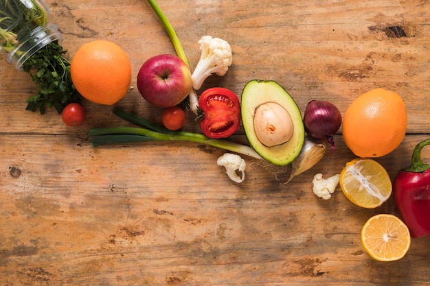 Frutas y verduras frescas dispuestas en una fila en la mesa de madera