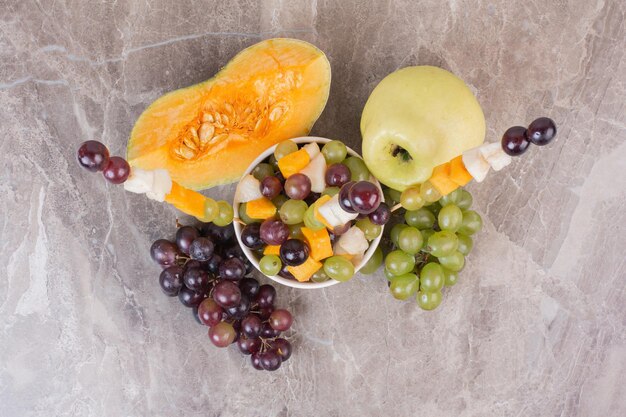 Frutero y frutas frescas sobre superficie de mármol.