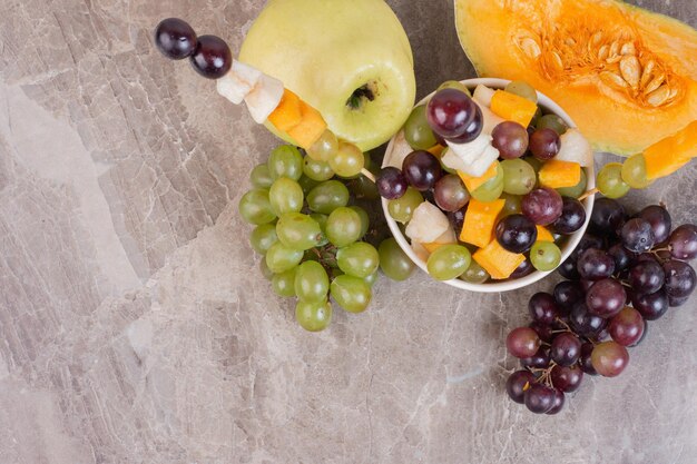 Frutero y frutas frescas sobre superficie de mármol.