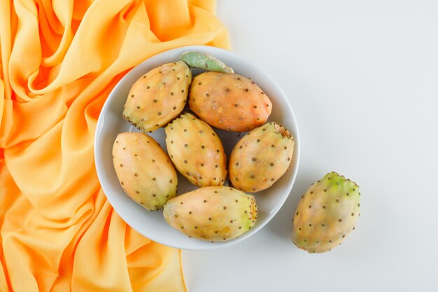 Frutos de cactus en un plato blanco sobre la superficie textil amarilla