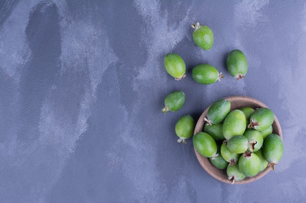 Frutos de feijoa en una taza de madera sobre superficie azul