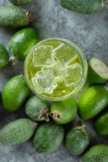 Frutos de feijoa y vaso de jugo en la superficie de mármol.