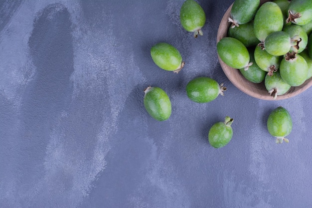 Foto gratuita frutos de feijoa verde en una taza de madera en el cuadro azul.