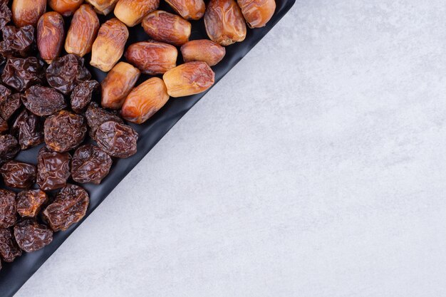 Frutos secos con dátiles y cerezas en un plato de madera. Foto de alta calidad