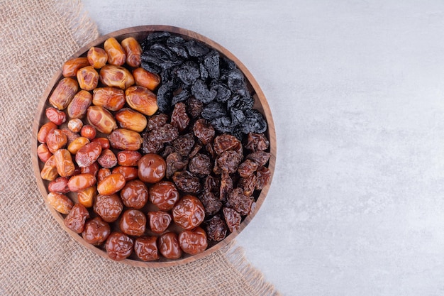 Frutos secos con dátiles y cerezas en un plato de madera. Foto de alta calidad