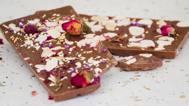 Frutos secos y pétalos de rosa en barra de chocolate comido