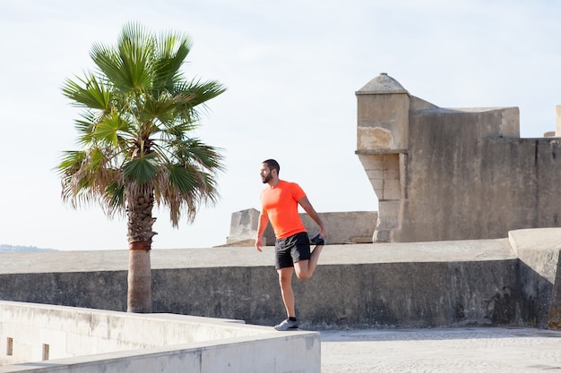 Foto gratuita fuerte, deportista, estirar, pierna, parapet