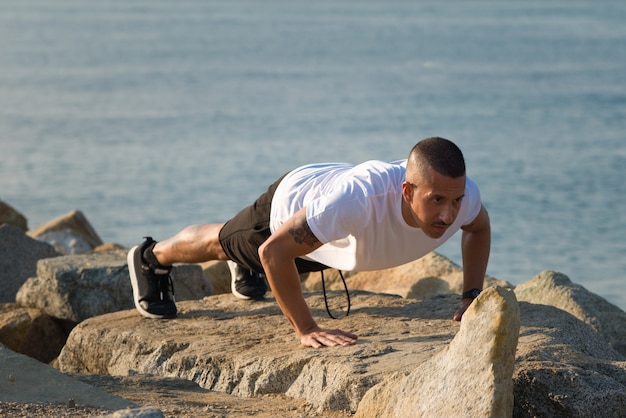 Fuerte, joven, hombre, actuación, push-ups, piedra