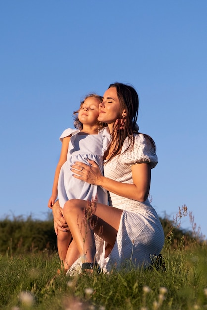 Full shot smiley madre y niña al aire libre