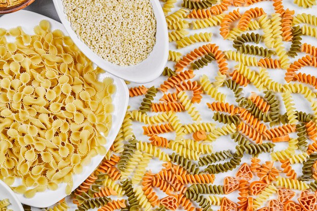 Foto gratuita fusilli colorido y otras pastas crudas en blanco.