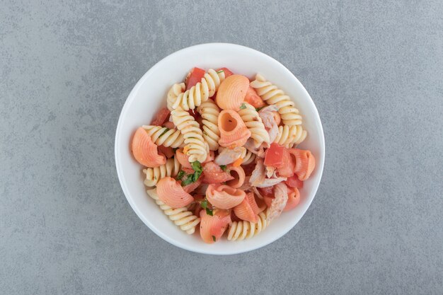 Fusilli y pasta de concha roja en un tazón blanco.