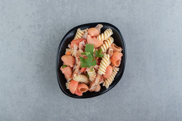 Fusilli y pasta de concha roja en un tazón negro.