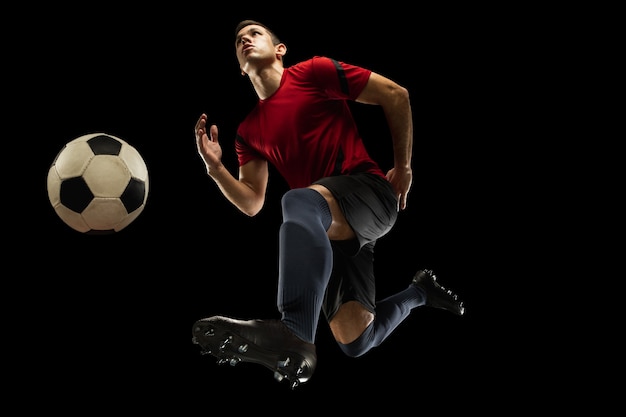 Fútbol caucásico joven, jugador de fútbol en acción, movimiento aislado sobre fondo negro