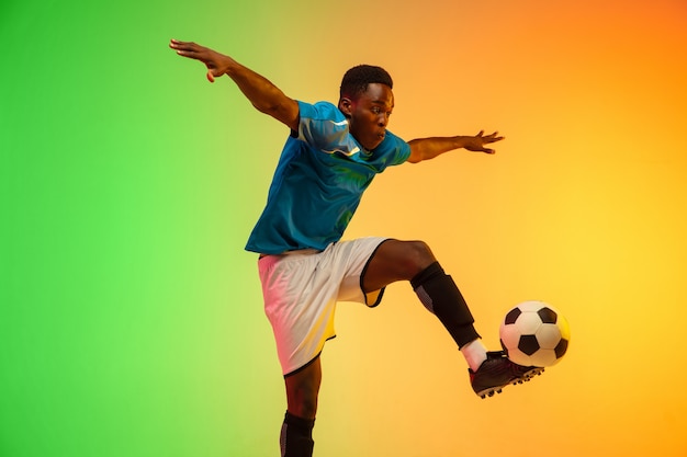 Fútbol masculino, entrenamiento de jugador de fútbol en acción aislado en estudio degradado en luz de neón