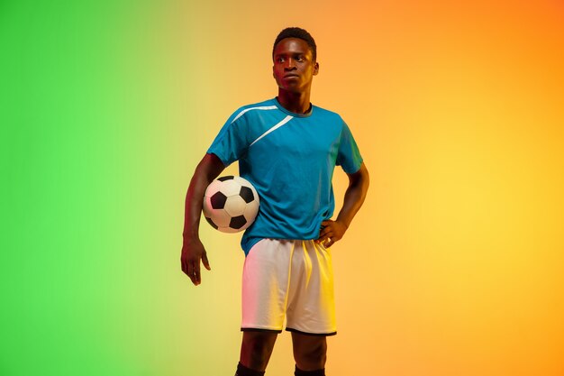 Fútbol masculino, entrenamiento de jugador de fútbol en acción aislado en estudio degradado en luz de neón