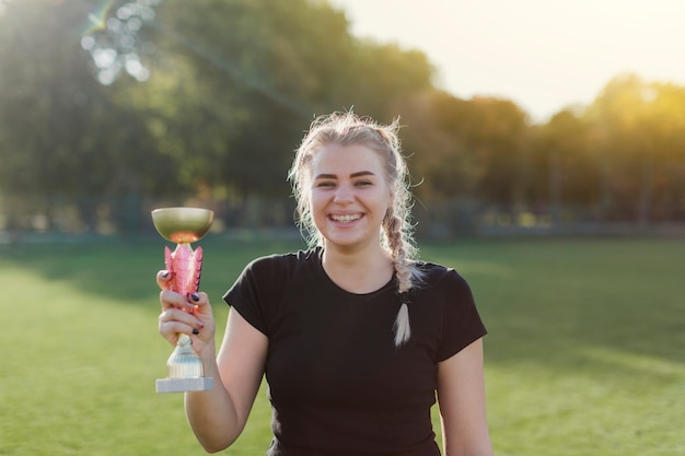 Futbolista femenino sosteniendo un trofeo