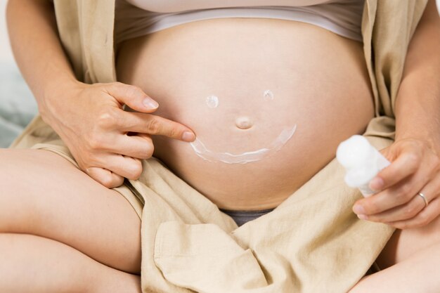 Futura madre dibujando una sonrisa con crema