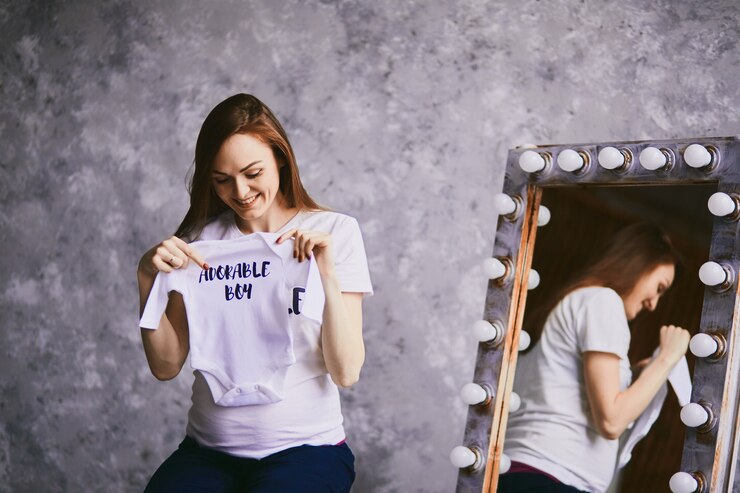 Foto gratuito la futura madre guarda una camisa para el bebé.