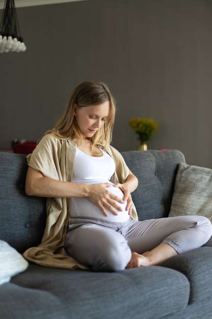 Foto gratuita futura madre sentada en el sofá