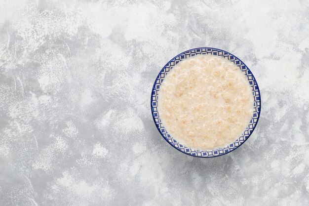 Gachas de avena en un recipiente sobre hormigón, vista superior