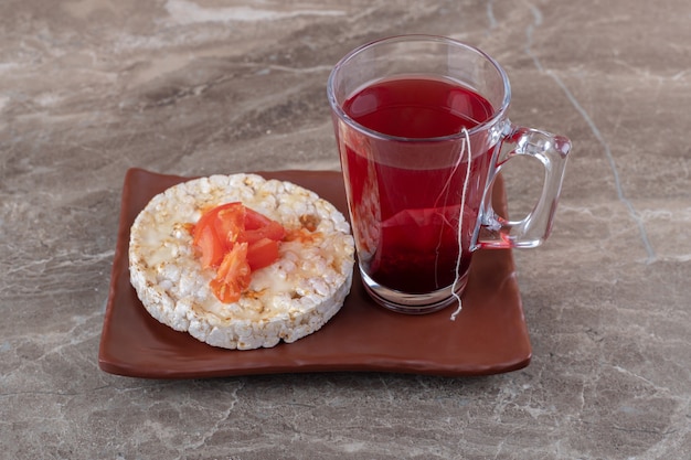 Gachas de avena con rodajas de tomate en un vaso sobre una placa de madera, sobre la superficie de mármol