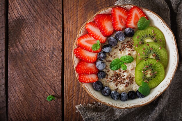 Gachas de avena sabrosas y saludables con frutas, bayas y semillas de lino. Desayuno saludable. Comida de fitness. Nutrición apropiada. Endecha plana. Vista superior