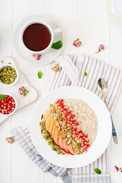 Gachas de avena sabrosas y saludables con manzanas, granadas y nueces. Desayuno saludable. Comida de fitness. Nutrición apropiada. Vista superior.