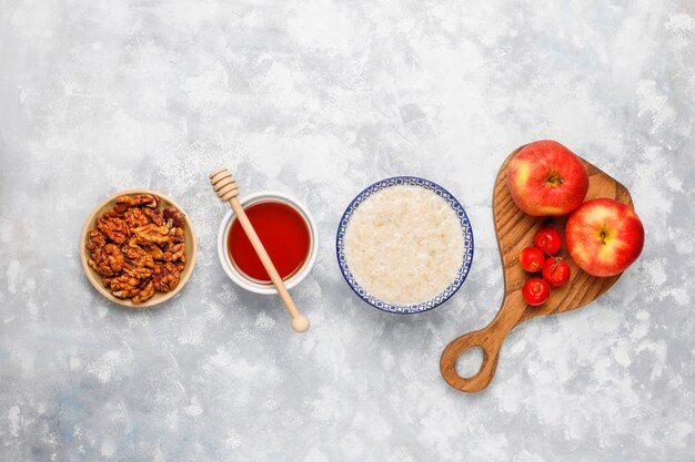 Gachas de avena en un tazón con rodajas de manzana roja y miel, vista superior