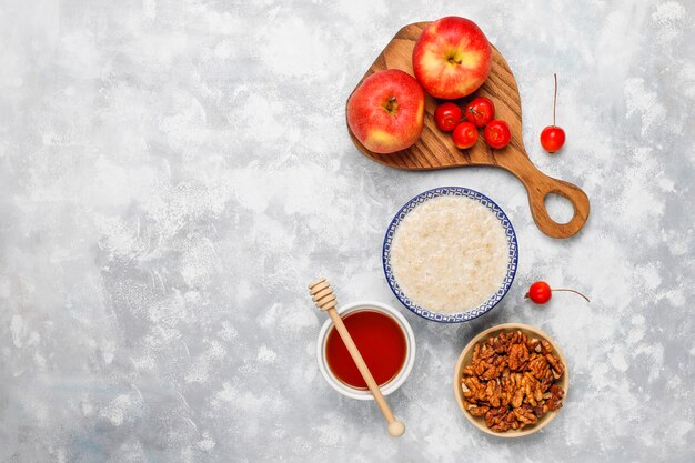 Gachas de avena en un tazón con rodajas de manzana roja y miel, vista superior