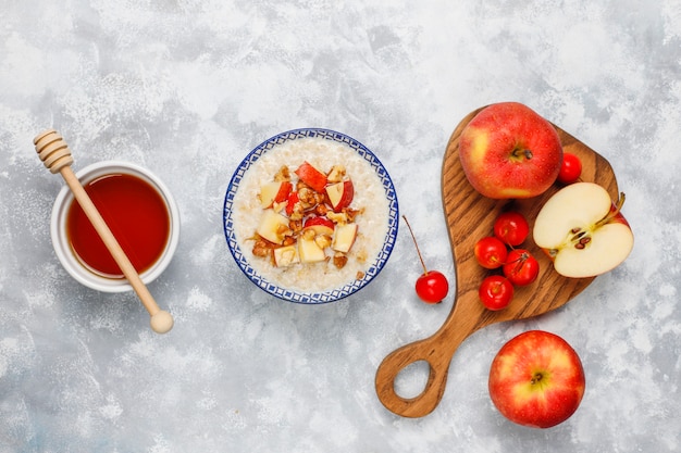 Gachas de avena en un tazón con rodajas de manzana roja y miel, vista superior