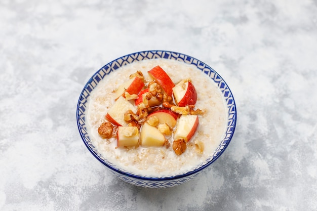 Gachas de avena en un tazón con rodajas de manzana roja y miel, vista superior