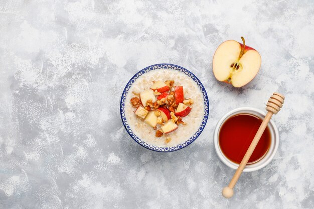 Gachas de avena en un tazón con rodajas de manzana roja y miel, vista superior