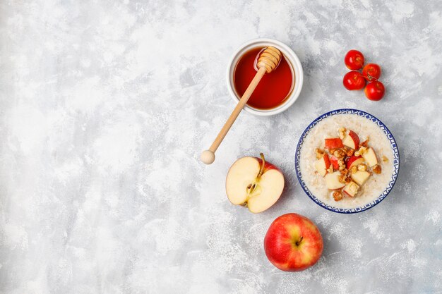 Gachas de avena en un tazón con rodajas de manzana roja y miel, vista superior