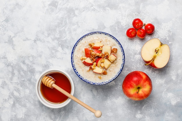 Gachas de avena en un tazón con rodajas de manzana roja y miel, vista superior