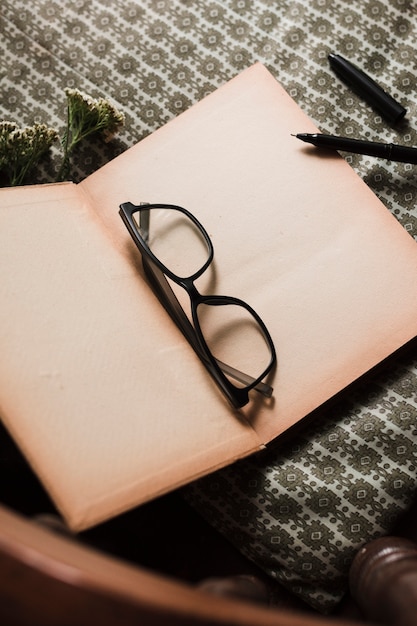 Foto gratuita gafas y bolígrafos sobre libro abierto