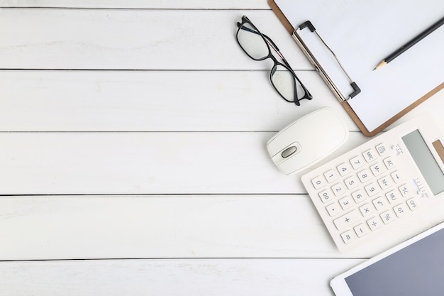 Gafas, calculadora y tableta en blanco escritorio aseado