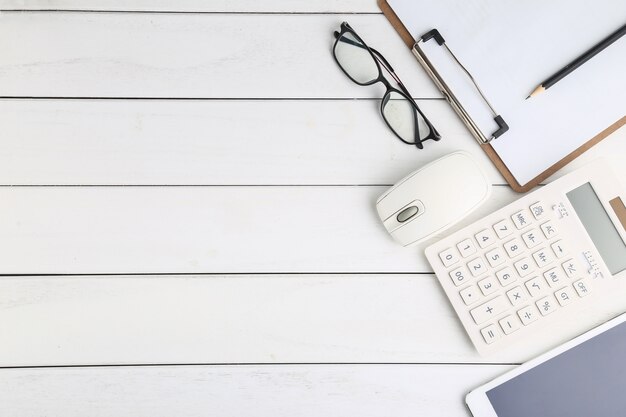 Gafas, calculadora y tableta en blanco escritorio aseado